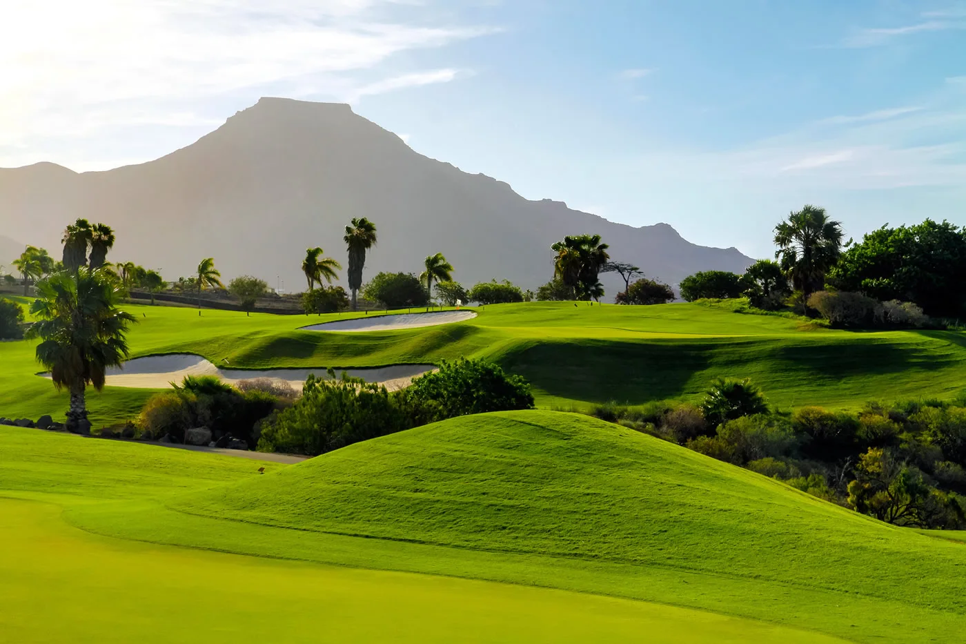 Costa Adeje green and sculpted bunkers with mountains behind