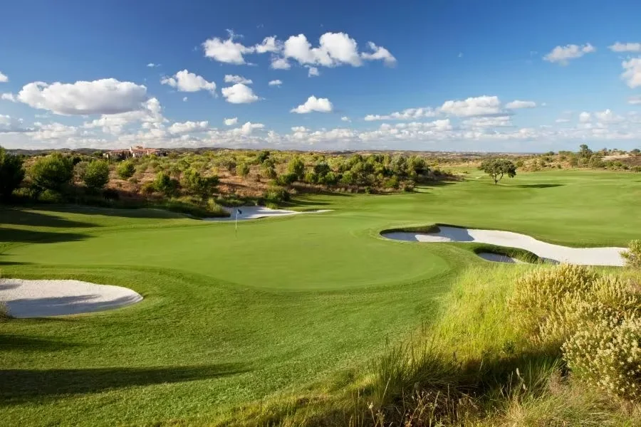 Monte Rei North Course green with white sand bunkers under a blue sky · On-site golf